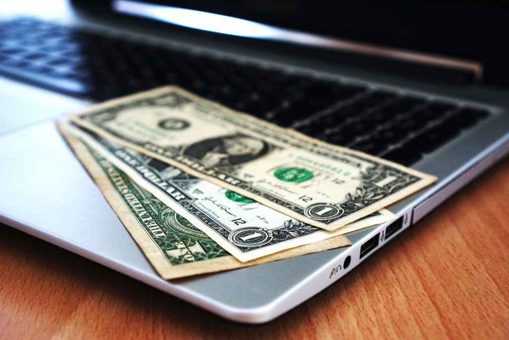 Computer on desk with dollars on the keyboard